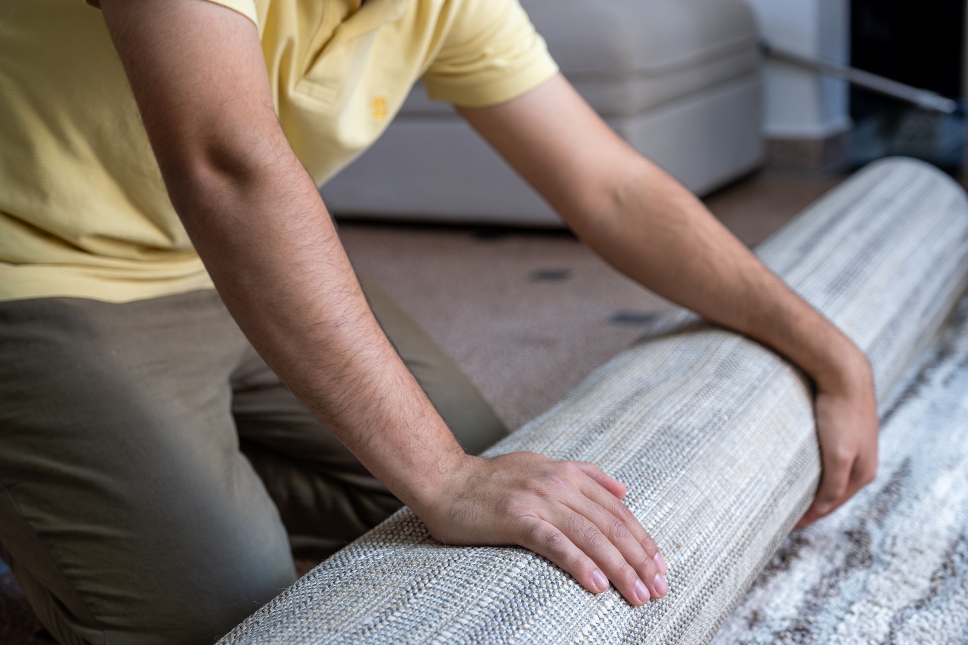 Smiling Man Rolling Out Carpet in Modern Living Room
